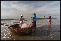 Fishermen folding fishing net into coracle boat. Mui Ne, Vietnam ( color)