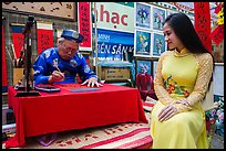 Caligrapher draws lunar new year greetings for beautiful woman in ao ai. Ho Chi Minh City, Vietnam ( color)