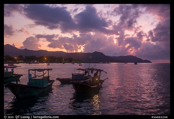 Men with light on fishing boat at dawn, Con Son harbor. Con Dao Islands, Vietnam (color)