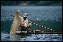 Fisherman retrieves net from a dugout boat. Northeast Vietnam (color)