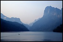Dugout boat in Ba Be Lake, surrounded by tall cliffs, early morning. Northeast Vietnam (color)