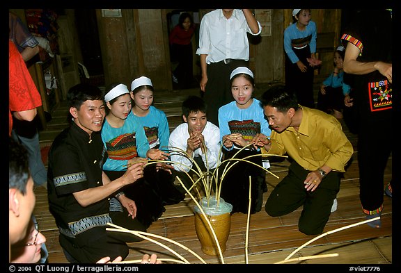 Thai women and guests drinking rau can alcohol with long straws, Ban Lac, Mai Chau. Northwest Vietnam (color)