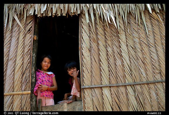 Children pear through a traditional hut. Hong Chong Peninsula, Vietnam