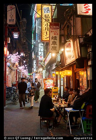 Dinners at outside table in alley at night, Shinjuku. Tokyo, Japan (color)