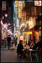Dinners at outside table in alley at night, Shinjuku. Tokyo, Japan ( color)