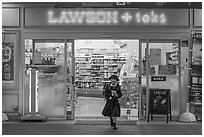 Girl in school uniform walking out of convenience store. Tokyo, Japan ( black and white)