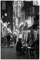 Dinners at outside table in alley at night, Shinjuku. Tokyo, Japan ( black and white)
