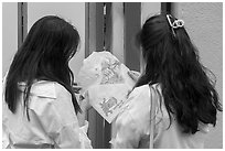 Women share tako senbei, snack made with roasted octopus pressed into a crispy sheet. Enoshima Island, Japan ( black and white)