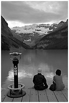 Couple sitting at the edge of Lake Louise at dawn. Banff National Park, Canadian Rockies, Alberta, Canada ( black and white)