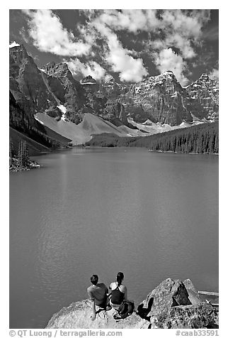 Couple sitting on the edge of Moraine Lake. Banff National Park, Canadian Rockies, Alberta, Canada (black and white)