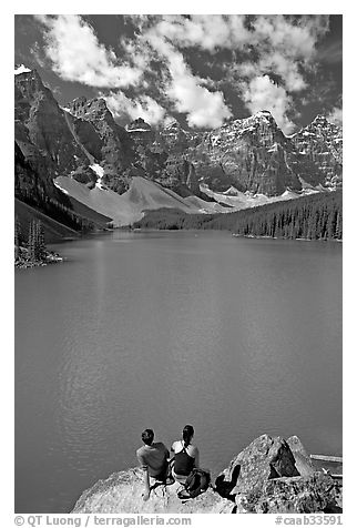 Couple sitting on the edge of Moraine Lake. Banff National Park, Canadian Rockies, Alberta, Canada