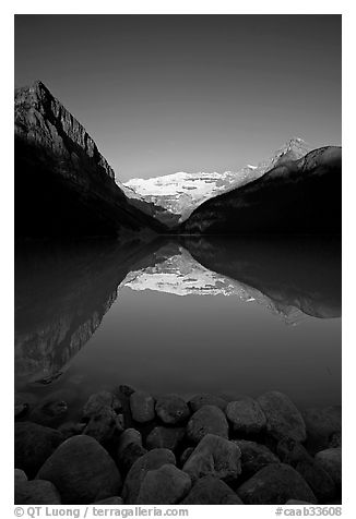 Boulders, Mirror-like Lake Louise and Victoria Peak, early morning. Banff National Park, Canadian Rockies, Alberta, Canada (black and white)