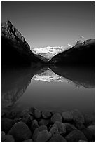 Boulders, Mirror-like Lake Louise and Victoria Peak, early morning. Banff National Park, Canadian Rockies, Alberta, Canada ( black and white)