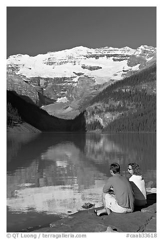 Couple sitting in the sun in front of Lake Louise, morning. Banff National Park, Canadian Rockies, Alberta, Canada (black and white)