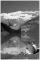 Couple sitting in the sun in front of Lake Louise, morning. Banff National Park, Canadian Rockies, Alberta, Canada ( black and white)
