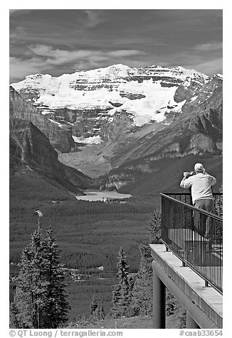 Man looking at Lake Louise through binoculars on observation platform. Banff National Park, Canadian Rockies, Alberta, Canada