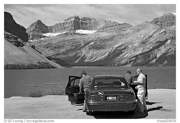 Tourists stepping out of a car next to Bow Lake. Banff National Park, Canadian Rockies, Alberta, Canada