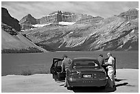 Tourists stepping out of a car next to Bow Lake. Banff National Park, Canadian Rockies, Alberta, Canada (black and white)