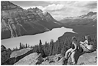 Tourists sitting on a rook overlooking Peyto Lake. Banff National Park, Canadian Rockies, Alberta, Canada ( black and white)