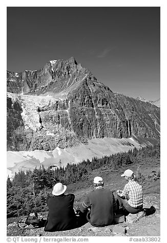 Hikers sitting in front of Mt Edith Cavell next to trail. Jasper National Park, Canadian Rockies, Alberta, Canada