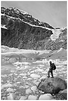 Hiker with backpack looking at iceberg-filed lake, glaciers, and mountain, Mt Edith Cavell. Jasper National Park, Canadian Rockies, Alberta, Canada (black and white)