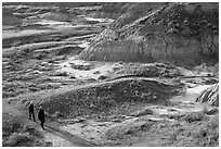 Hikers amongst badlands, morning, Dinosaur Provincial Park. Alberta, Canada (black and white)