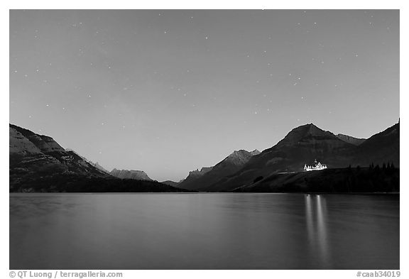 Waterton lake by night with stars in the sky in lights of Price of Wales Hotel. Waterton Lakes National Park, Alberta, Canada