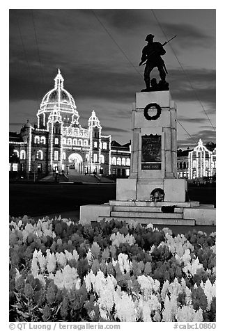 Flowers, memorial statue and illuminated parliament building at night. Victoria, British Columbia, Canada (black and white)
