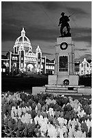 Flowers, memorial statue and illuminated parliament building at night. Victoria, British Columbia, Canada (black and white)