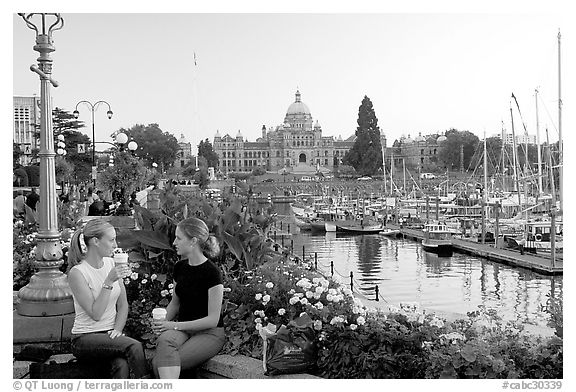 Women drinking coffee at the Inner Harbour, sunset. Victoria, British Columbia, Canada (black and white)