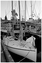 Girl swinging from the mast of a small sailboat, Inner Harbour. Victoria, British Columbia, Canada (black and white)