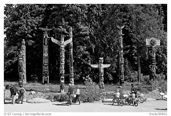 Tourists loooking at Totems, Stanley Park. Vancouver, British Columbia, Canada