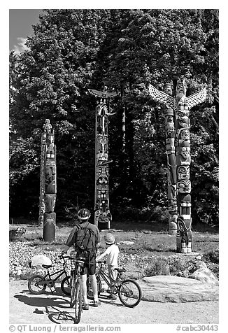 Family with bicycles looking at Totems, Stanley Park. Vancouver, British Columbia, Canada