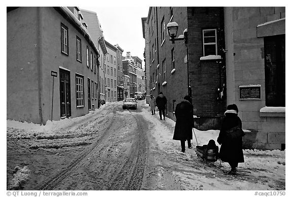 Residents pulling a sled with a child in a street, Quebec City. Quebec, Canada (black and white)