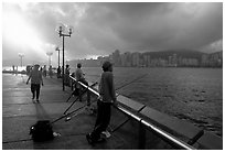 Fishing on the waterfront promenade, sunrise. Hong-Kong, China (black and white)