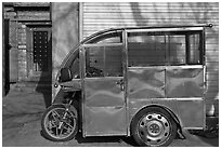 Enclosed scooter on sidewalk. Beijing, China (black and white)