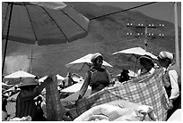Bai women examining a piece of cloth at the Monday market. Shaping, Yunnan, China (black and white)