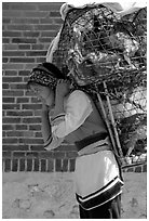 Woman carrying a load of chicken cages on forehead. Shaping, Yunnan, China (black and white)