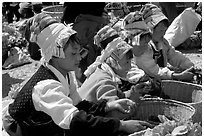 Bai women in tribal dress selling vegetables at the Monday market. Shaping, Yunnan, China (black and white)