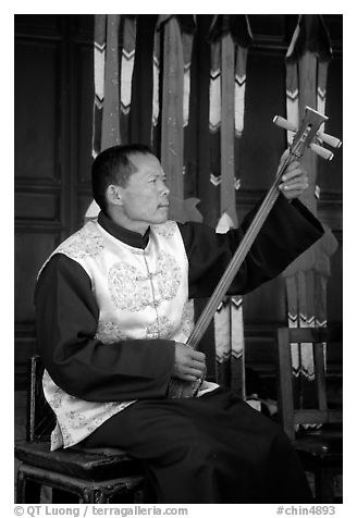 Musician playing a three-stringed traditional moon guitar. Baisha, Yunnan, China (black and white)