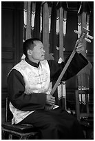 Musician playing a three-stringed traditional moon guitar. Baisha, Yunnan, China (black and white)