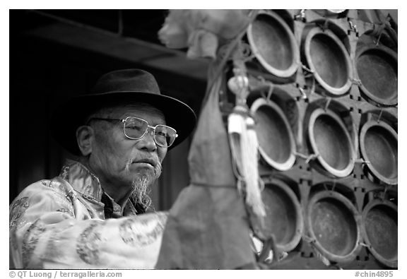 Elderly  musician playing a traditional percussion instrument. Baisha, Yunnan, China (black and white)