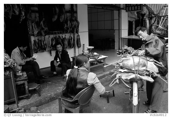 Loading roasted meat on a bicycle. Kunming, Yunnan, China