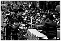 Woman checking out her bicycle at a bicycle lot. Kunming, Yunnan, China (black and white)