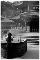 Woman offers incense in the central courtyard of Yantong Si. Kunming, Yunnan, China (black and white)
