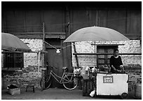 Foot stand in front of a wooden building. Kunming, Yunnan, China (black and white)