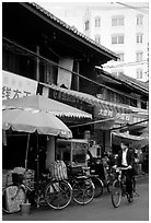 Man on bicycle in front of wooden buildings. Kunming, Yunnan, China ( black and white)