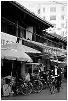 Man on bicycle in front of wooden buildings. Kunming, Yunnan, China (black and white)