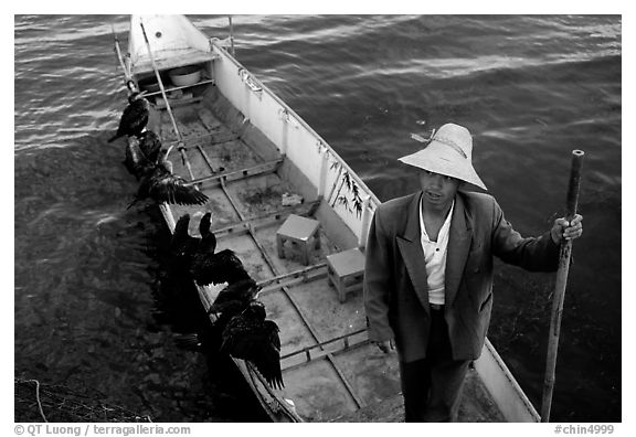 Cormorant Fisherman in a boat with his fishing birds. Dali, Yunnan, China (black and white)