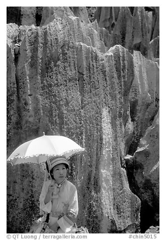 Woman from the Sani branch of the Yi tribespeople with a sun unbrella at the Stone Forest. Shilin, Yunnan, China (black and white)